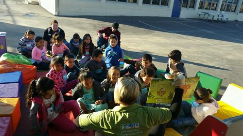 children looking at woman holding a book